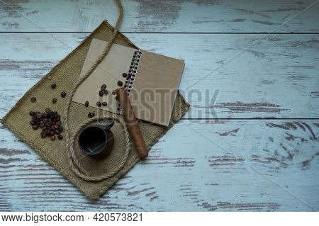 Empty Coffee Cup, Coffee Beans, Cigar, Notepad, Brown Napkin Isolated On Wood Background. Copyspace