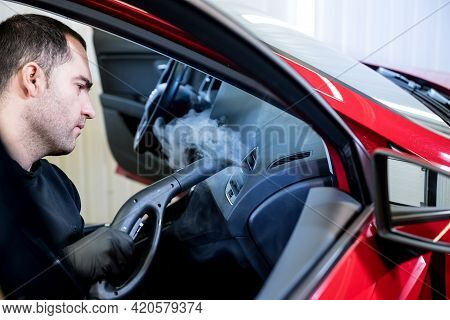 Car Service Worker Cleans Interiror With Steam Cleaner