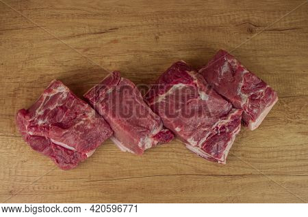 a big piece of raw pork neck on a wooden table. close-up, copy space