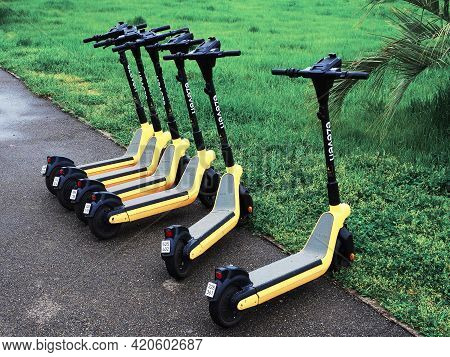 Russia, Sochi 16.04.2021. Several Black And Yellow Electric Scooters Are Parked On The Asphalt Along