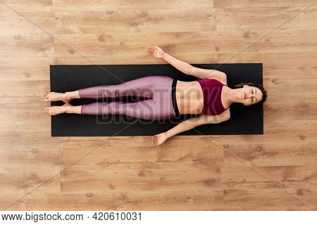 fitness, sport and healthy lifestyle concept - woman doing yoga corpse pose at studio