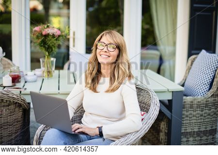 Attractive Cheerful Woman Using Laptop While Sitting In The Balcony At Home