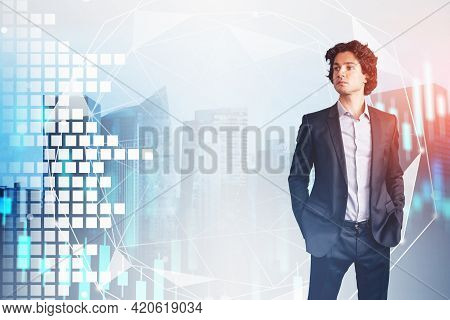 Portrait Of Handsome Businessman In Black Suit Looking At Financial Data Chart, Hands In Pockets. St