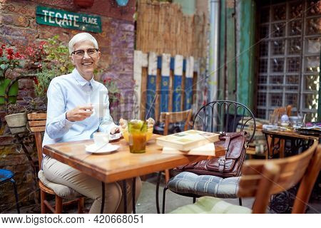 An older woman posing for a photo while having a coffee in a relaxed atmopshere in the bar. Leisure, bar, friendship, outdoor