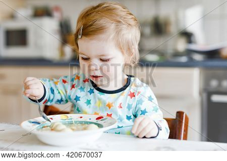 Adorable Baby Girl Eating From Spoon Vegetable Noodle Soup. Food, Child, Feeding And Development Con
