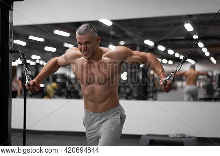 Muscular Athletic Bodybuilder Standing Training Chest And Shoulders Muscles On Fitness Equipment Wir