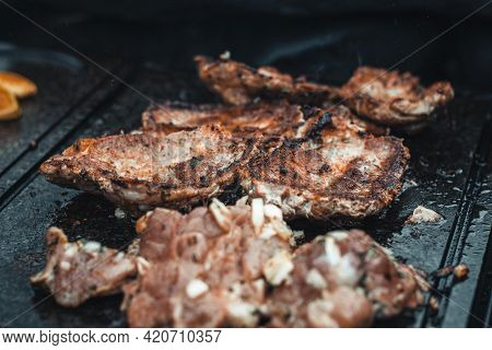 Man Slices A Pork Neck, Fragrant And Richly Seasoned With Basil, Pepper, Salt And Other Herbs, Which