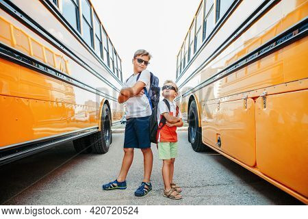 Back To School. Caucasian Brothers Students Standing By Yellow School Bus. Cool Kids In Sunglasses G