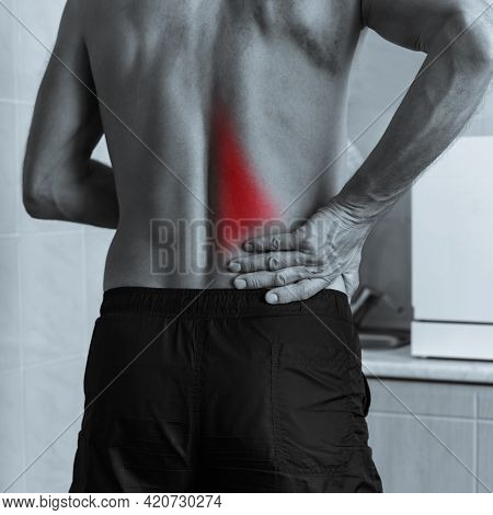 Monochrome Photo Of Muscular Man Holding His Aching Back With Hand
