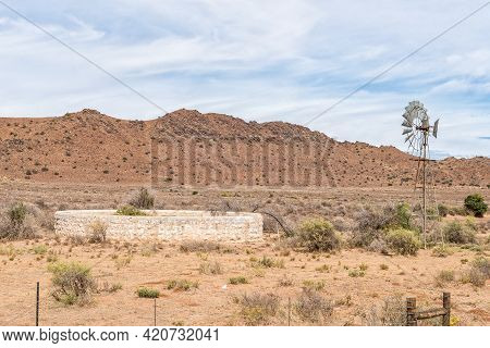 A Windmill And Dam Next To Road N1 Between Richmond And Three Sisters In The Northern Cape Karoo