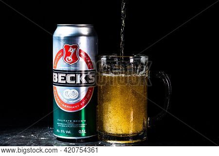 Can Of Beck`s Or Becks Beer And Beer Glass On Dark Background. Illustrative Editorial Photo Shot In 