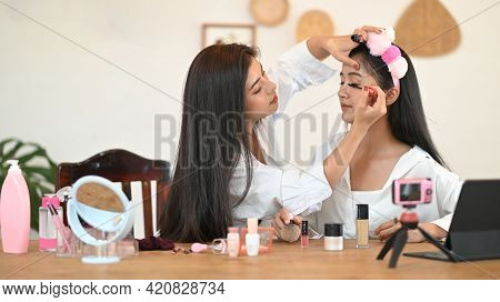 Women Are Showing How To Make Up Via Online Video At The Wooden Dressing Table.