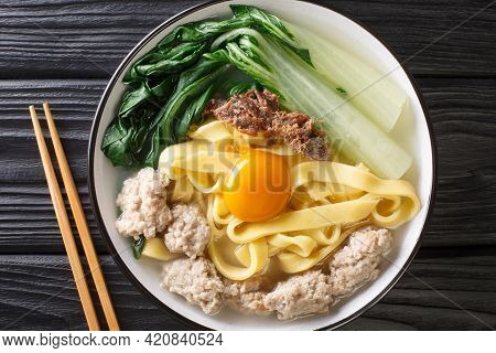 Ban Mian Chinese Egg Noodle Soup With Anchovies, Meatballs And Pak Choi Close-up In A Bowl On The Ta