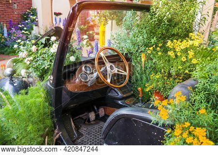 Flowers grow in the car, the original design of the classic vintage car interior, close up on steering wheel, dasboard, retro effect