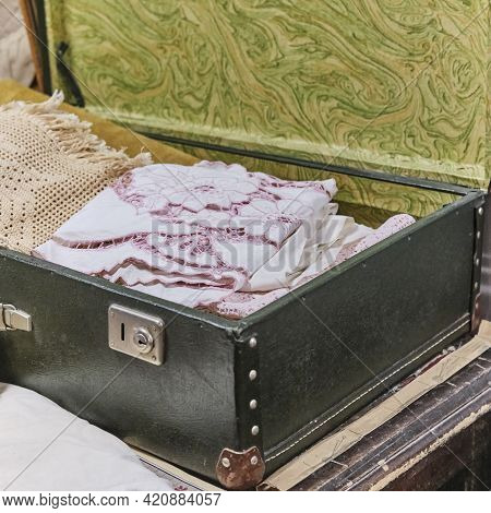 An Antique White Handmade Tablecloth With Cutwork Embroidery Lies In An Old Suitcase.