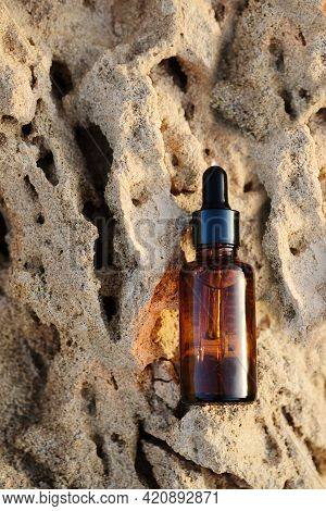 Amber Glass Spray Bottle With White Blank Label On Rock Stone On Beige Background. Natural Organic C