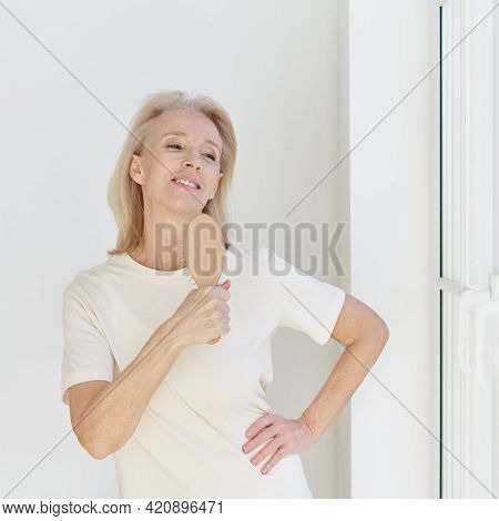 Happy Carefree Mature Woman With Hairbrush As Mic Singing Her Favourite Song And Having Fun At Home.