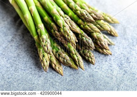 Close-up Detail Bunch Of Fresh Raw Green Asparagus Plant Harvested At Season On Blue Rustic Fabric K