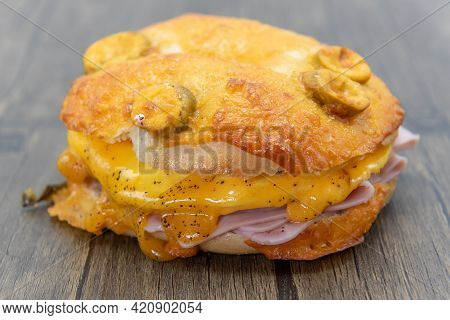 Melted Cheese Dripping Over The Stacks Of Sliced Ham Served Inside A Jalepeno Breakfast Bagel Cut In