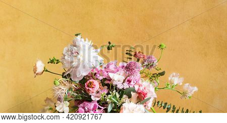 Flowers in a vase by a yellow wall