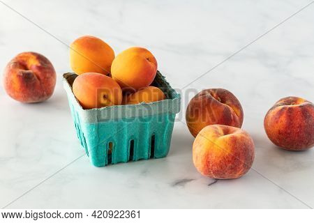 An Assortment Of Apricots And Peaches Against A Light Background.