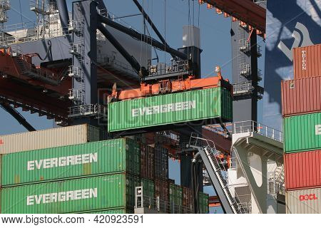 Rotterdam, The Netherlands - Circa 2019: Containers being unloaded from a huge cargo ship in the Euromax container terminal of the Port of Rotterdam. Gantry cranes work lifting Evergreen containers