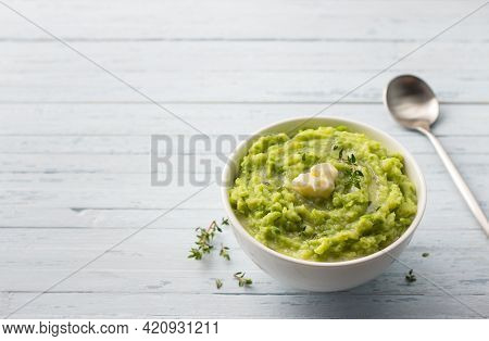 Delicate Mashed Potatoes With Green Peas, Flavored With Butter, Spices And Thyme On A Light Blue Bac