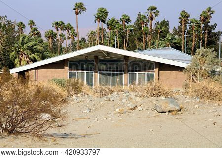 Creosote Shrubs On A Sandy Desert Field Besides A Retro Style Building With 1950s Architectural Desi