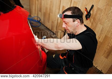 Car Service Worker Put Anti Gravel Film On A Red Car Body At The Detailing Vehicle Workshop. Car Pro