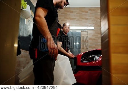 Car Service Worker Put Anti Gravel Film On A Red Car Body At The Detailing Vehicle Workshop. Car Pro