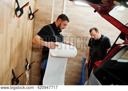 Car Service Worker Put Anti Gravel Film On A Red Car Body At The Detailing Vehicle Workshop. Car Pro