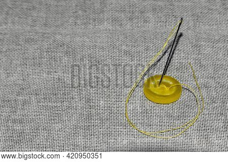 The Yellow Button Is Sewn With A Sewing Needle And Yellow Thread To Hold The Two Fabrics Together In