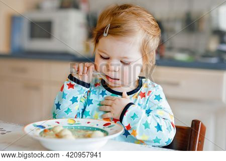 Adorable Baby Girl Eating From Spoon Vegetable Noodle Soup. Food, Child, Feeding And Development Con