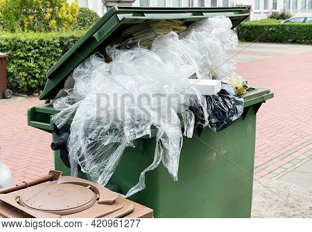 Green Garbage Container Bin Overflowing With Plastic Packaging Waste