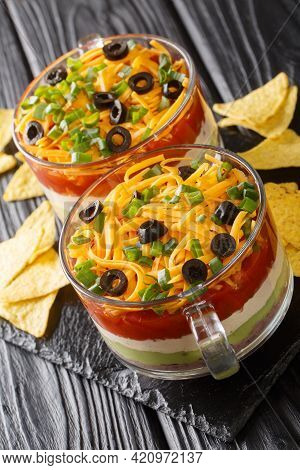 Super Bowl 7 Layer Dip With Tortilla Chips Close Up In The Glass On The Table. Vertical