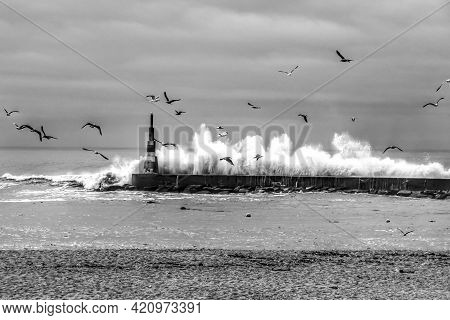 Giant Waves Breaking On The Breakwater And The Lighthouse On Aguda Beach, Miramar, Arcozelos Town