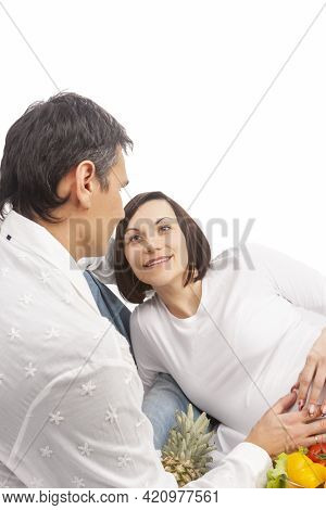 Caucasian Couple With Pregnant Wife Laying Together Over White Background. Vertical Image