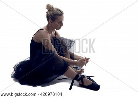Caucasian Ballet Dancer In Body Suit Preparing For Dance While Sitting On White Floor Against White