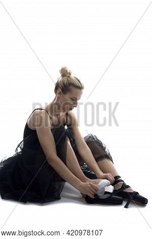 Caucasian Ballet Dancer In Body Suit Preparing For Dance While Sitting On White Floor Against White