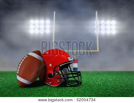 Football And Helmet On Field With Goal Post Under Spotlights