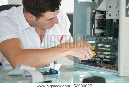 Handsome computer engineer repairing computer with pliers in bright office