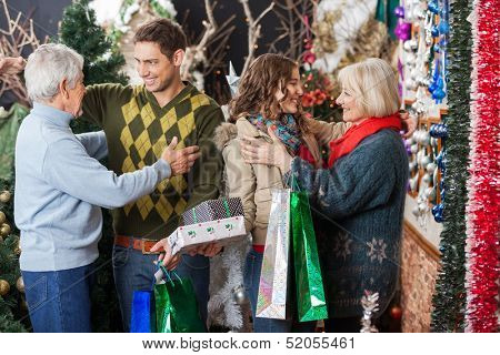 Happy family with shopping bags and presents embracing each other in Christmas store