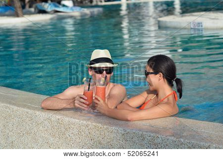 happy young couple relax and take fresh drink at summer vacation on swimmin pool