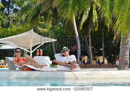 happy young couple relax and take fresh drink at summer vacation on swimmin pool