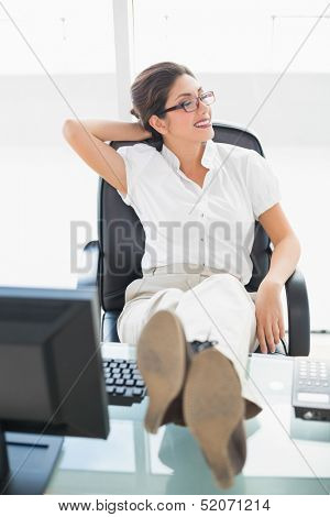 Relaxed businesswoman sitting at her desk with her feet up in her office