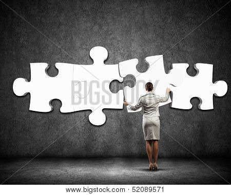 Image of businesswoman connecting elements of white puzzle