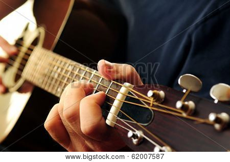 Hands of a person playing an acoustic guitar close up