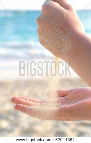Hands pouring fine sand on a beach