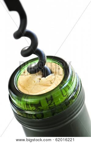Opening wine bottle with a corkscrew on white background