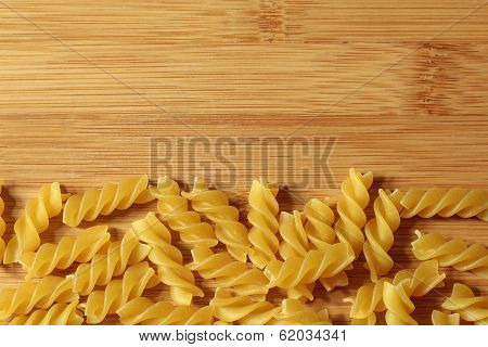 Uncooked Italian pasta noodles background on wooden texture